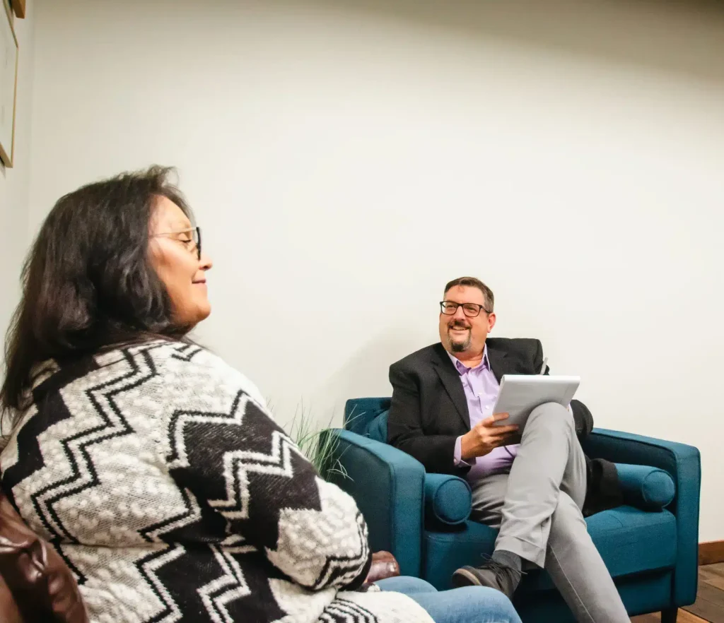 A man and woman are seated in a room, talking and smiling. (Copy)