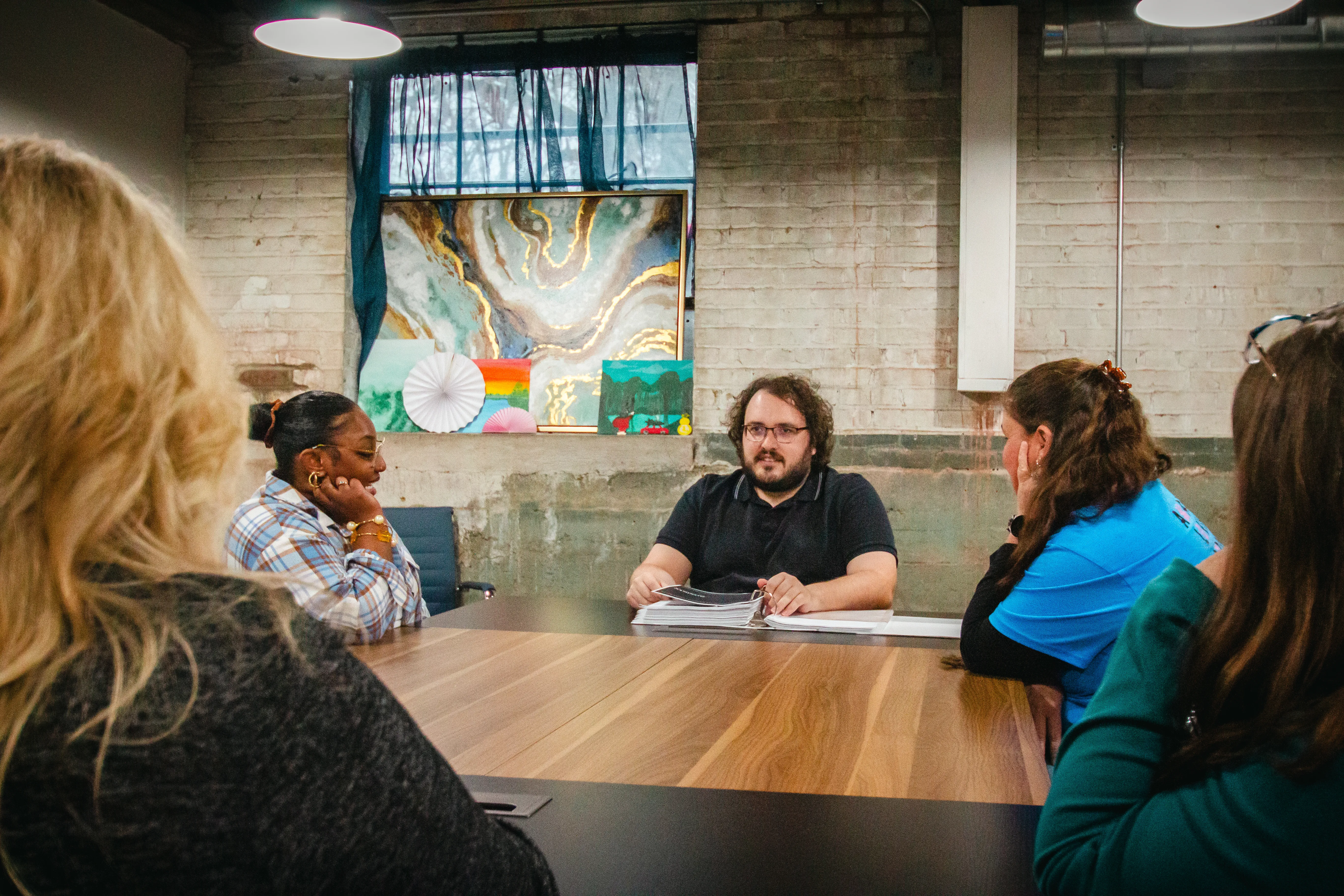A group of five people engaged in a meeting around a conference table.