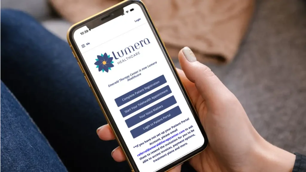 Person holding a smartphone displaying a Lumera Healthcare webpage interface.