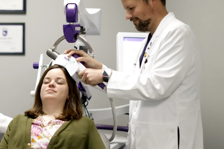 A doctor administers a transcranial magnetic stimulation treatment to a relaxed patient.